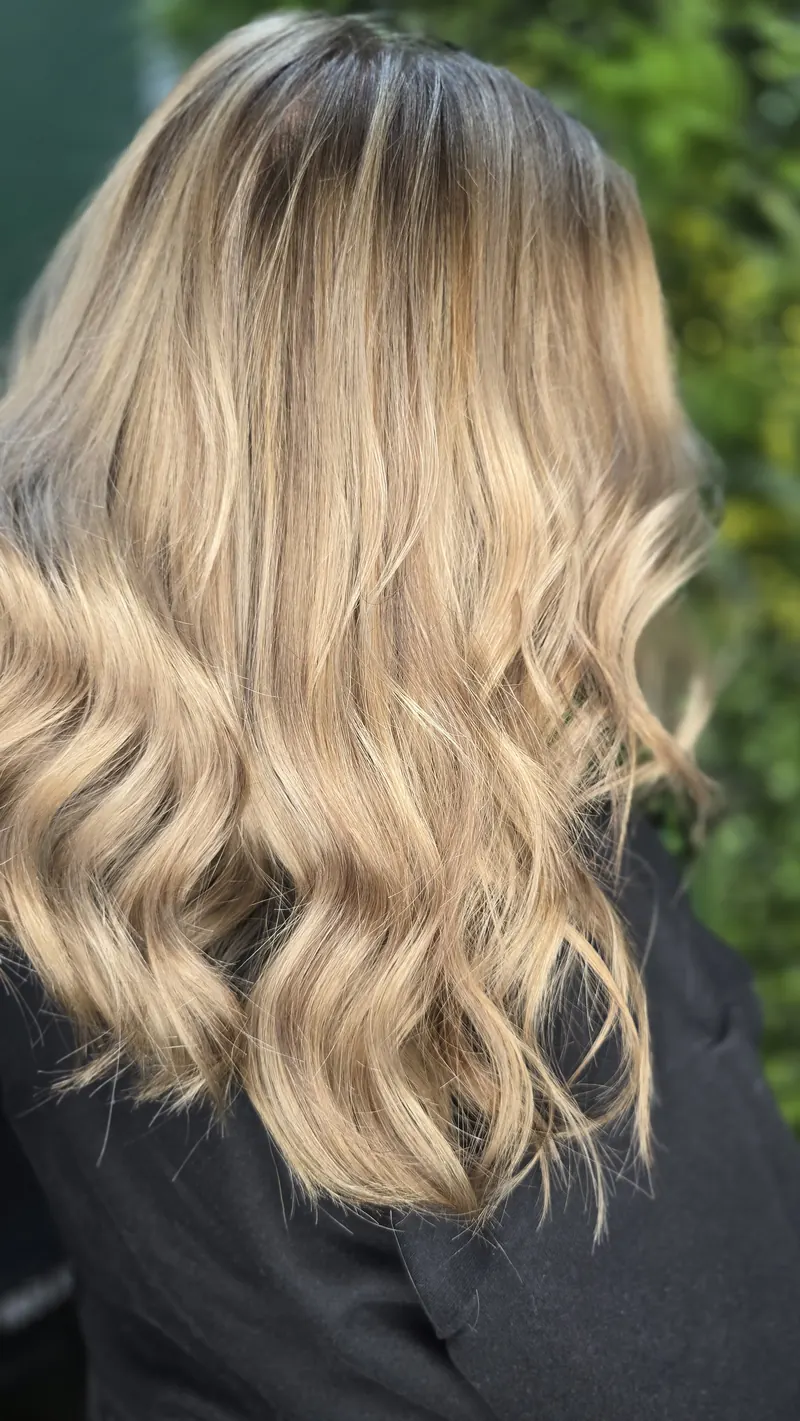 A side view of the same long waves with beige and honey balayage — hair by Jowita Litwin, Goleniów